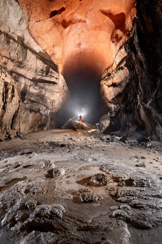 Cueva Fresca (Cantabrie, Espagne) - Grande galerie au plafond orange avec personnage en fond perché sur un rocher. (SP-26-0943)
